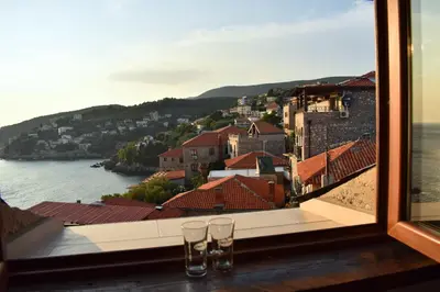 two glasses sitting on a ledge looking out a window at Villa Dulcinea in Ulcinj