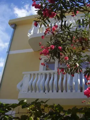 a white balcony with pink flowers in front of a building at Apartments Beba Zalad in Sutomore