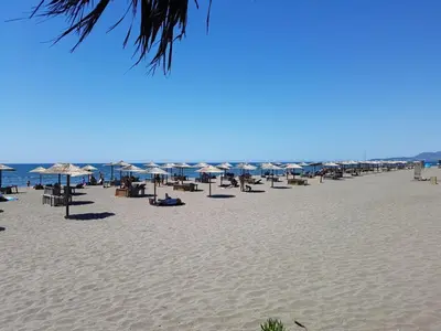 a beach with umbrellas and chairs and the ocean at Apartments Beba Zalad in Sutomore
