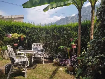 a patio with two chairs and a table in a garden at Apartman Art in Kotor