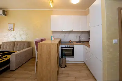 a small kitchen with white cabinets and a table at Krizor Apartman Budva in Budva