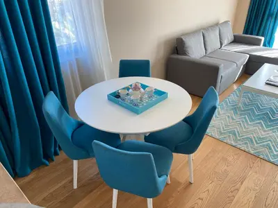 a living room with a white table and blue chairs at Apartment Sofia, City Centar in Podgorica