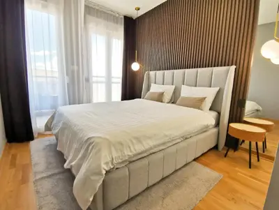 a bedroom with a large white bed and a table at Design Apartment at CITY QUART in Podgorica