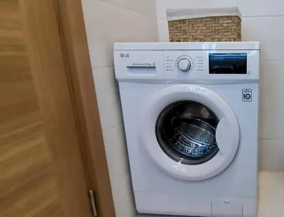 a white washing machine in a bathroom with a door at Design Apartment at CITY QUART in Podgorica