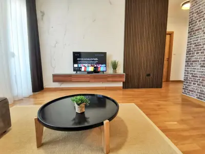 a black coffee table in a living room with a plant at Design Apartment at CITY QUART in Podgorica