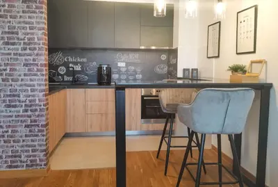 a kitchen with a counter and two stools at a bar at Design Apartment at CITY QUART in Podgorica