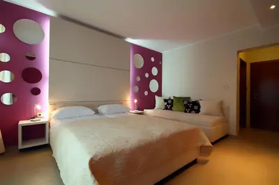 a bedroom with two beds and purple and white walls at Domador Rooms & Apartments in Budva