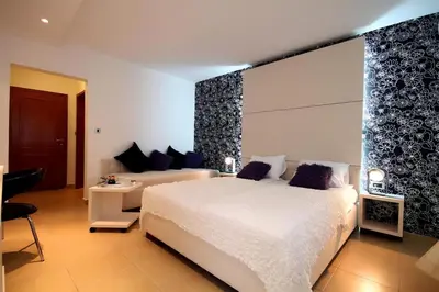 a bedroom with a large white bed and a couch at Domador Rooms & Apartments in Budva