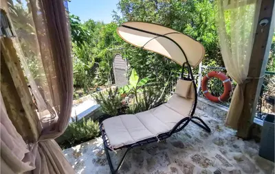 a swinging chair on the back porch of a house at Awesome Apartment In Utjeha With Wifi in Utjeha