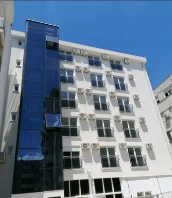 a tall white building with a lot of windows at Vi studio city center 2min to sea in Bar