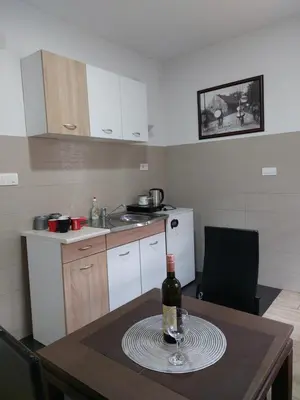 a small kitchen with a table with a bottle of wine at Apartments F in Podgorica