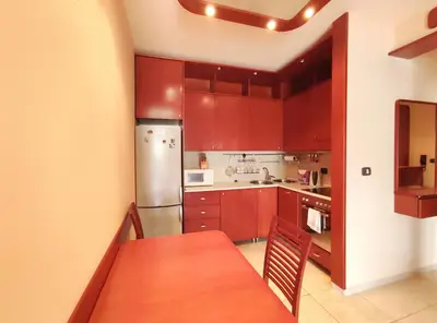 a kitchen with red cabinets and a table and a refrigerator at Apartments Altea in Rafailovici