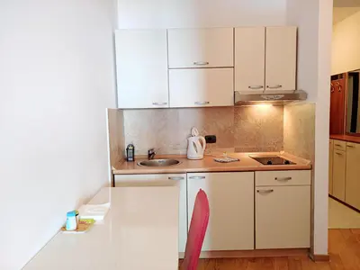 a small kitchen with white cabinets and a sink at Apartments Altea in Rafailovici