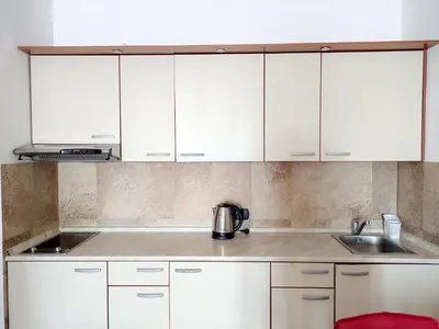 a kitchen with white cabinets and a sink at Apartments Altea in Rafailovici