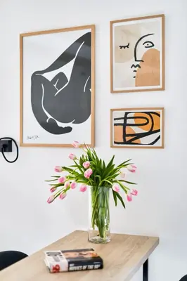 a vase of flowers on a table with paintings at Old Town Casa Dameo Apartments in Kotor