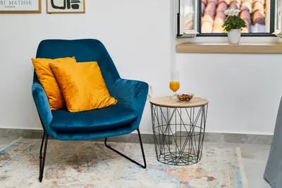 a blue chair with a yellow pillow next to a table at Old Town Casa Dameo Apartments in Kotor