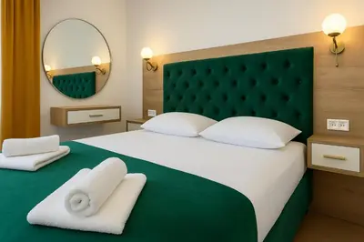 a bedroom with a large bed with a green headboard at Apartmani Enydoo in Ulcinj