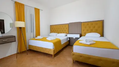 a hotel room with two beds and a television at Apartmani Enydoo in Ulcinj