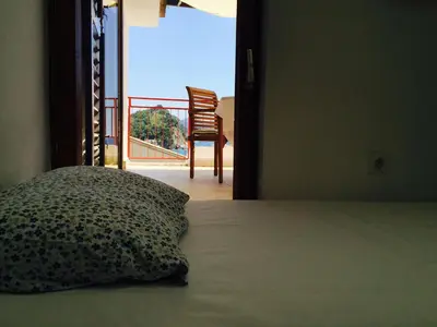 a bed with a pillow and a chair in a room at Apartments Almaja Villa in Petrovac na Moru