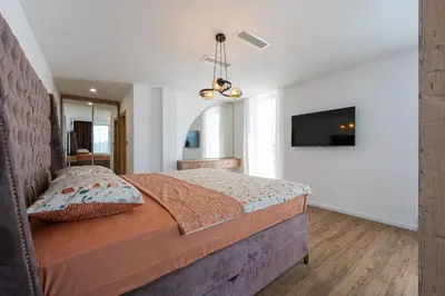 a bedroom with a large bed and a flat screen tv at Villa Una in Kotor