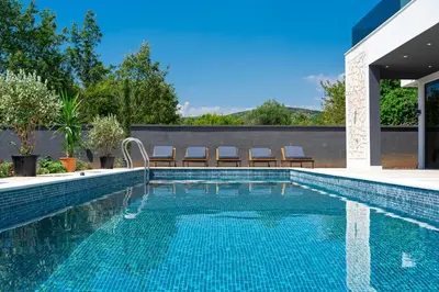 a swimming pool with chairs next to a house at Villa Una in Kotor