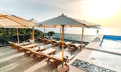 a patio with chairs and umbrellas next to a swimming pool at Kalamper Apartments in Dobra Voda
