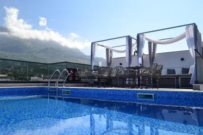 a swimming pool with chairs and a view of a mountain at Kalamper Apartments in Dobra Voda