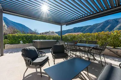 a patio with a blue table and chairs and mountains at Kotor Lux apartments and rooms in Kotor