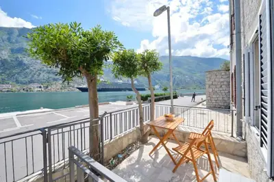 a balcony with a table and chairs and a view of the water at Cosy front line apt with sea access at your door step in Kotor