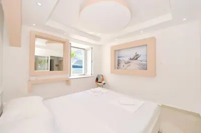 a white bedroom with two beds and a window at Cosy front line apt with sea access at your door step in Kotor