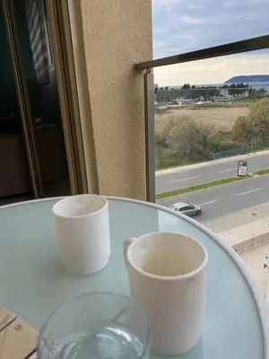 two cups sitting on a glass table with a window at Aleksandar First Sea Line Apartment in Bar