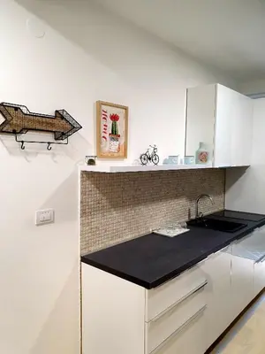 a kitchen with white cabinets and a black counter top at Aleksandar First Sea Line Apartment in Bar