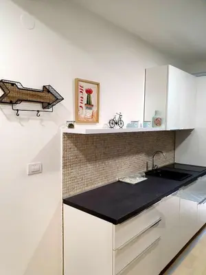 a kitchen with white cabinets and a black counter top at Aleksandar First Sea Line Apartment in Bar
