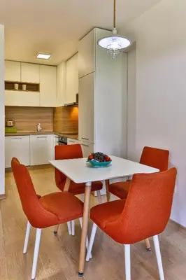 a kitchen with a white table and orange chairs at Montesun Fontana Apartments in Budva
