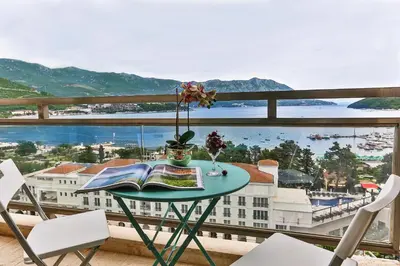 a table with a book and flowers on a balcony at Montesun Fontana Apartments in Budva