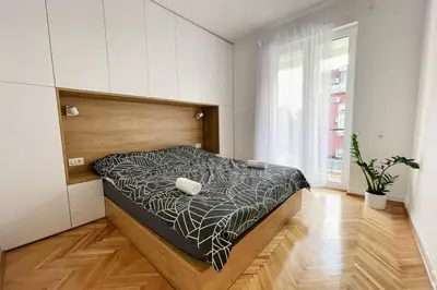 a bedroom with a bed with a black and white comforter at MILLENNIUM bridge cozy apartment TOP location in Podgorica