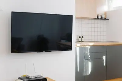 a flat screen tv hanging on a wall in a kitchen at MILLENNIUM bridge cozy apartment TOP location in Podgorica