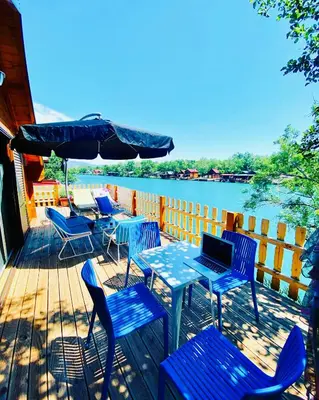 a deck with blue tables and chairs and a laptop at Mery Ada House in Ulcinj