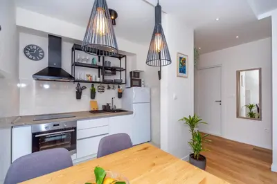 a kitchen with white cabinets and a table and chairs at Les appartements Privés Bar in Bar