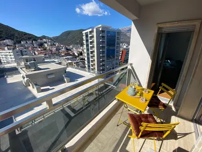 a balcony with a yellow table and chairs on a building at Four Views Apartments in Budva