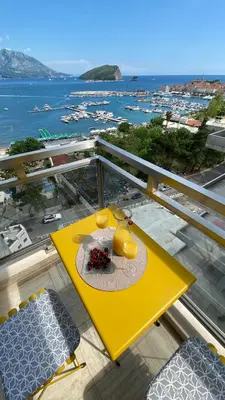 a yellow table on a balcony with a view of the ocean at Four Views Apartments in Budva