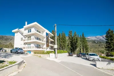 a white building with cars parked in a parking lot at HAPPY HOME in Tivat