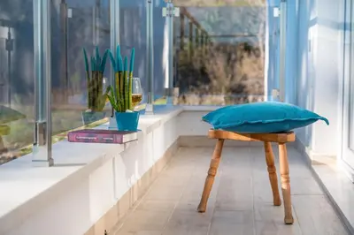 a bench with a blue pillow and a window at HAPPY HOME in Tivat
