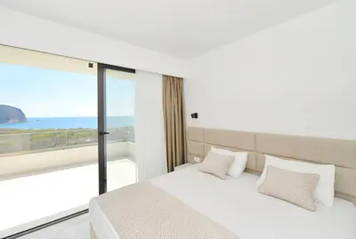 a bedroom with a white bed and a large window at Villa Zen Hill in Petrovac na Moru