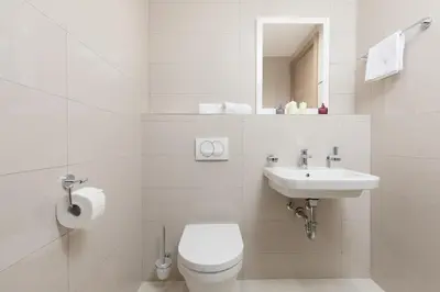 a white bathroom with a toilet and a sink at Carsko Selo Blizikuce in Budva