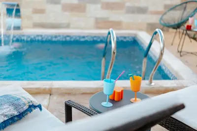 a table with two drinks on it next to a swimming pool at Villa Panorama Hill in Dobra Voda