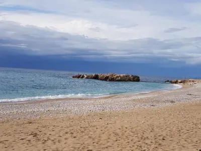 a sandy beach with a rock formation in the water at Villa Panorama Hill in Dobra Voda