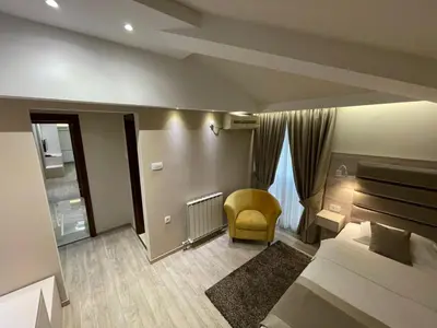 a bedroom with a bed and a yellow chair at Hotel Holiday in Podgorica