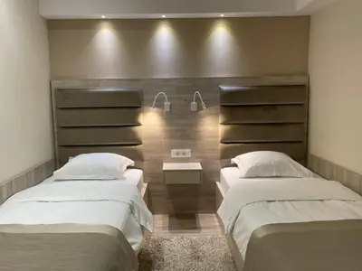 a bedroom with two beds and a wall with shelves at Hotel Holiday in Podgorica