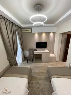 a hotel room with two beds and a desk at Hotel Holiday in Podgorica